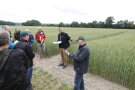 Ein Mitarbeiter der LfL steht in einem Feld vor mehreren Teilnehmern.