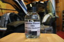 Laborglas mit paraffinischem Dieselkraftstoff vor einem Traktor am Prüfstand